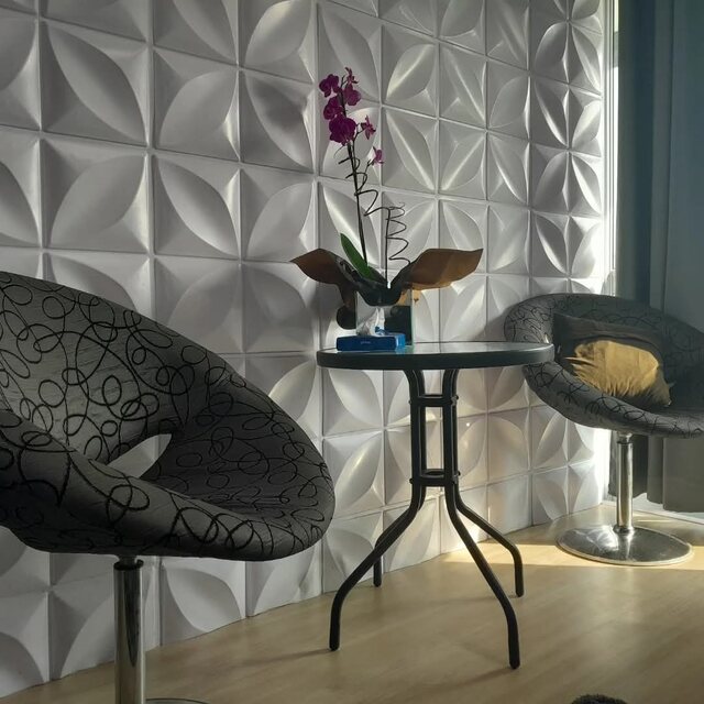 Espaço com duas poltronas e mesa de apoio, com parede texturizada e orquídea.